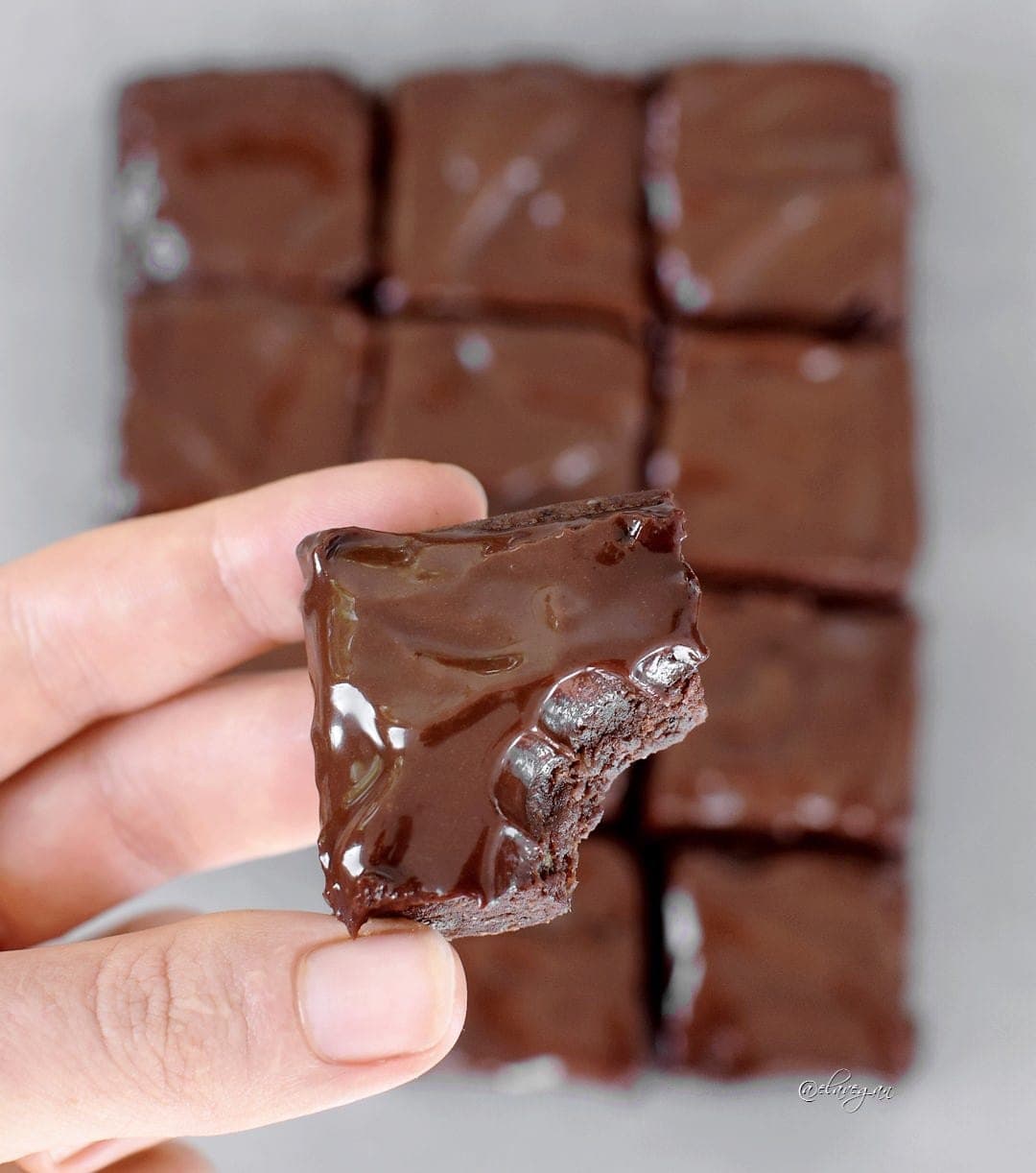 hand holding a raw brownie with bite marks