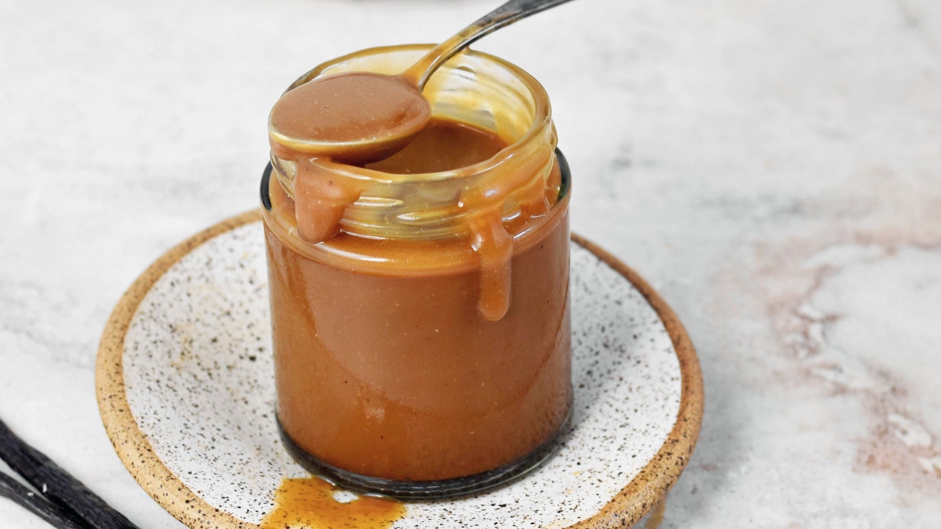 horizontal shot of vegan caramel sauce in jar with spoon