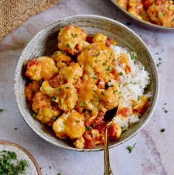 roasted cauliflower curry in bowl with rice and spoon