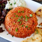 Greek tomato rice with vegan gyro tzatziki and pita chips on white plate