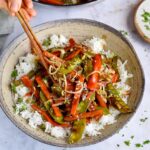eating vegan chop suey over rice with chopsticks