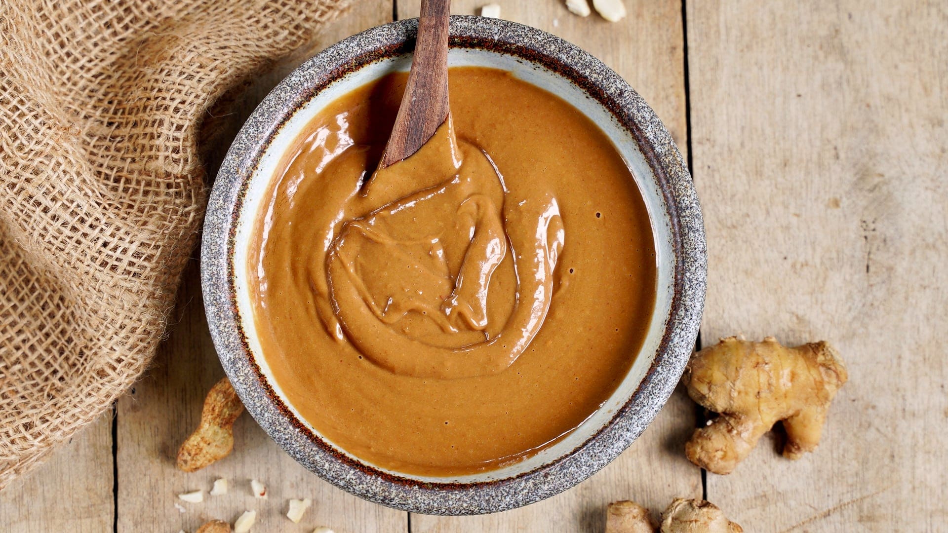 horizontal shot of peanut sauce with wooden spoon in bowl