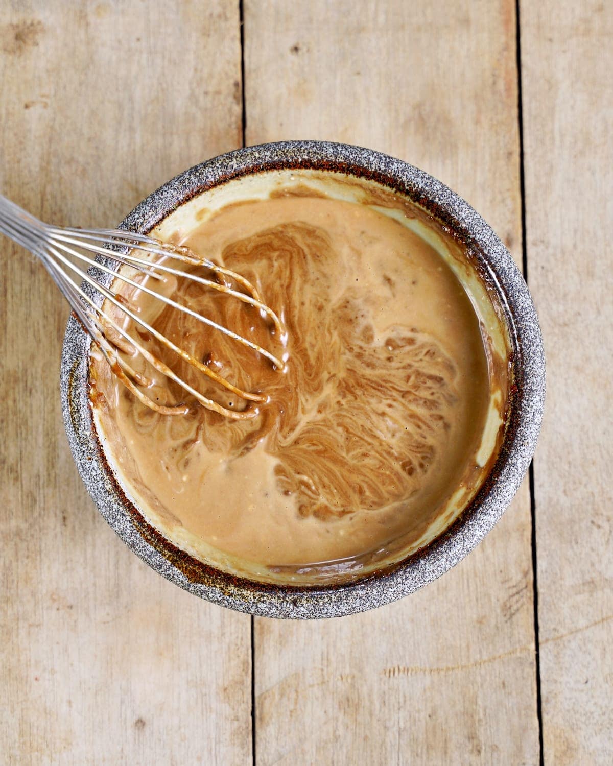 mixing peanut butter dressing in bowl with whisk