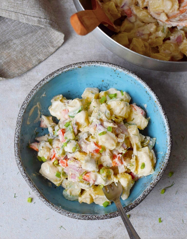 vegan potato salad in blue bowl with spoon