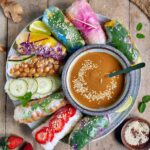 vegan summer rolls on large plate with peanut sauce in the middle