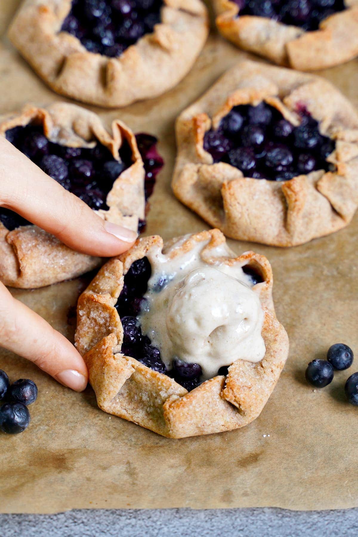 hand grabbing a blueberry galette with vegan ice cream