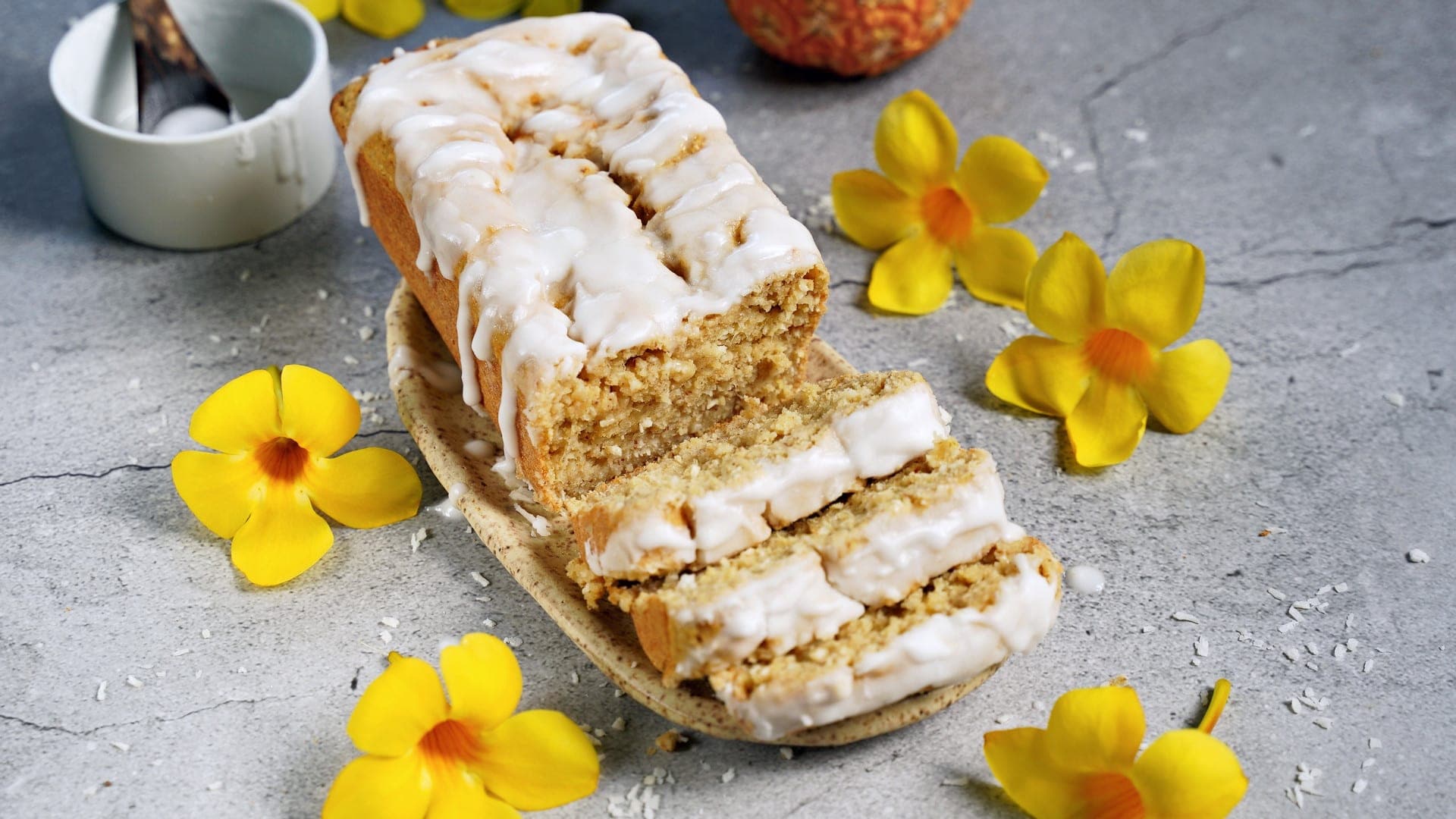 horizontal shot of pineapple bread with icing and yellow flowers