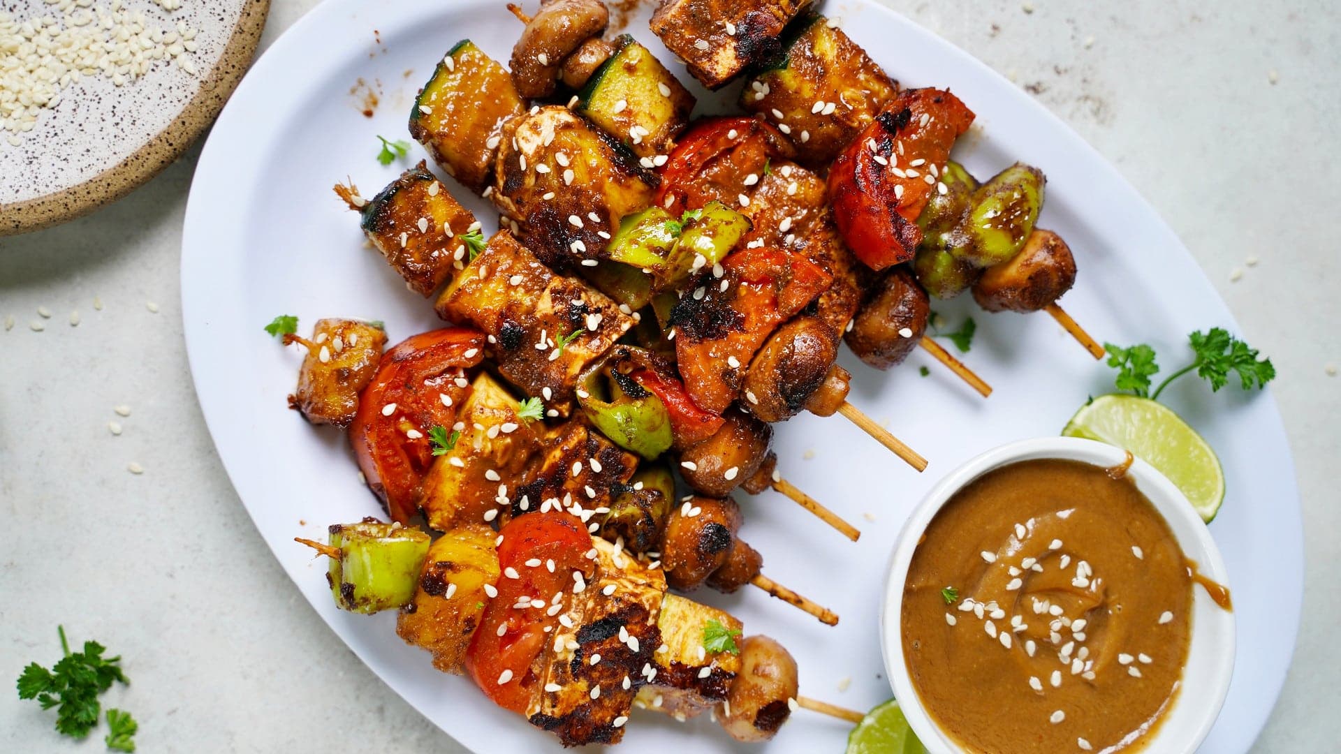 horizontal shot of vegetable kabobs with peanut sauce on white plate