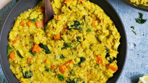 kitchari with veggies and moong dal in black bowl with spoon