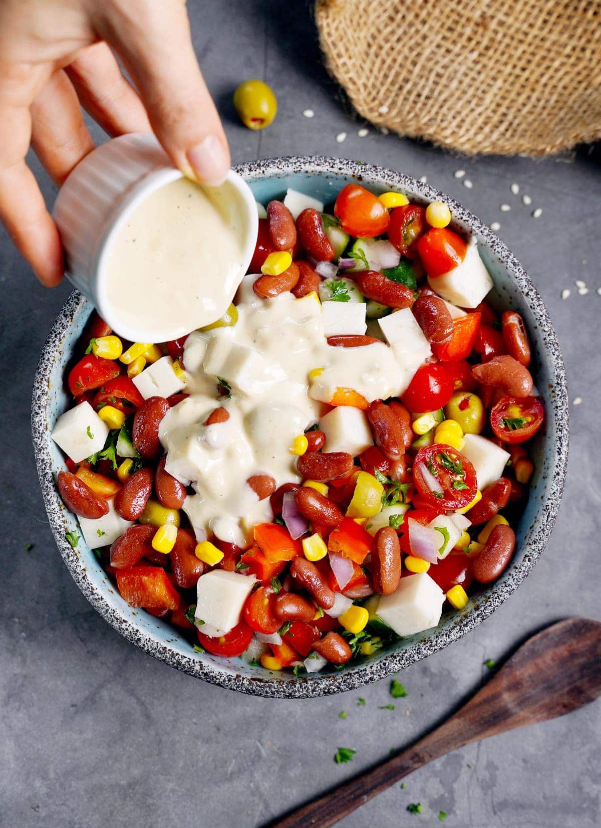 pouring tahini dressing over kidney bean salad
