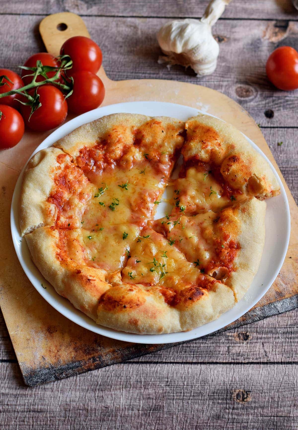der beste selbstgemachte Pizzateig mit Tomaten und veganem Käse auf weißem Teller