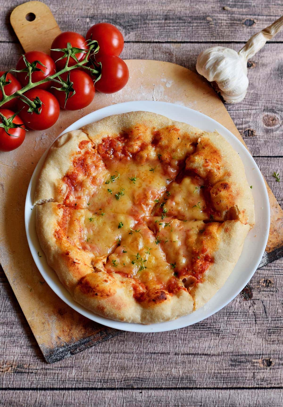 Aufnahme einer neapolitanischen Pizza mit Tomaten, Knoblauch und veganem Käse auf einem Teller