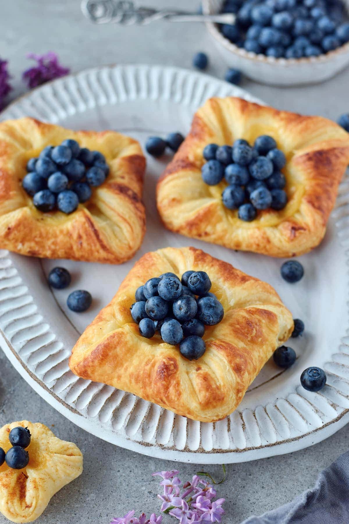 3 custard puff pastry treats on plate with berries