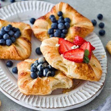 4 custard pastries with blueberries and strawberries on plate