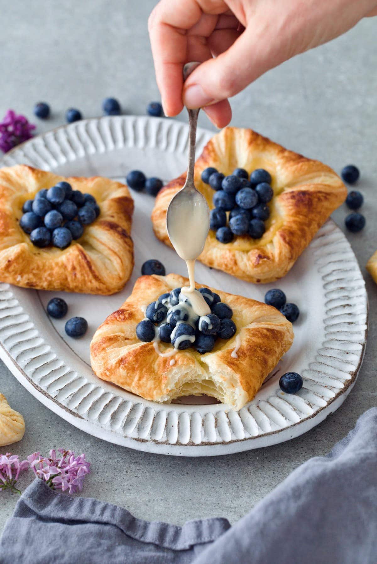 drizzling cashew butter over blueberry Danish pastry