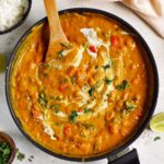 one pot pumpkin curry in black skillet with wooden spoon