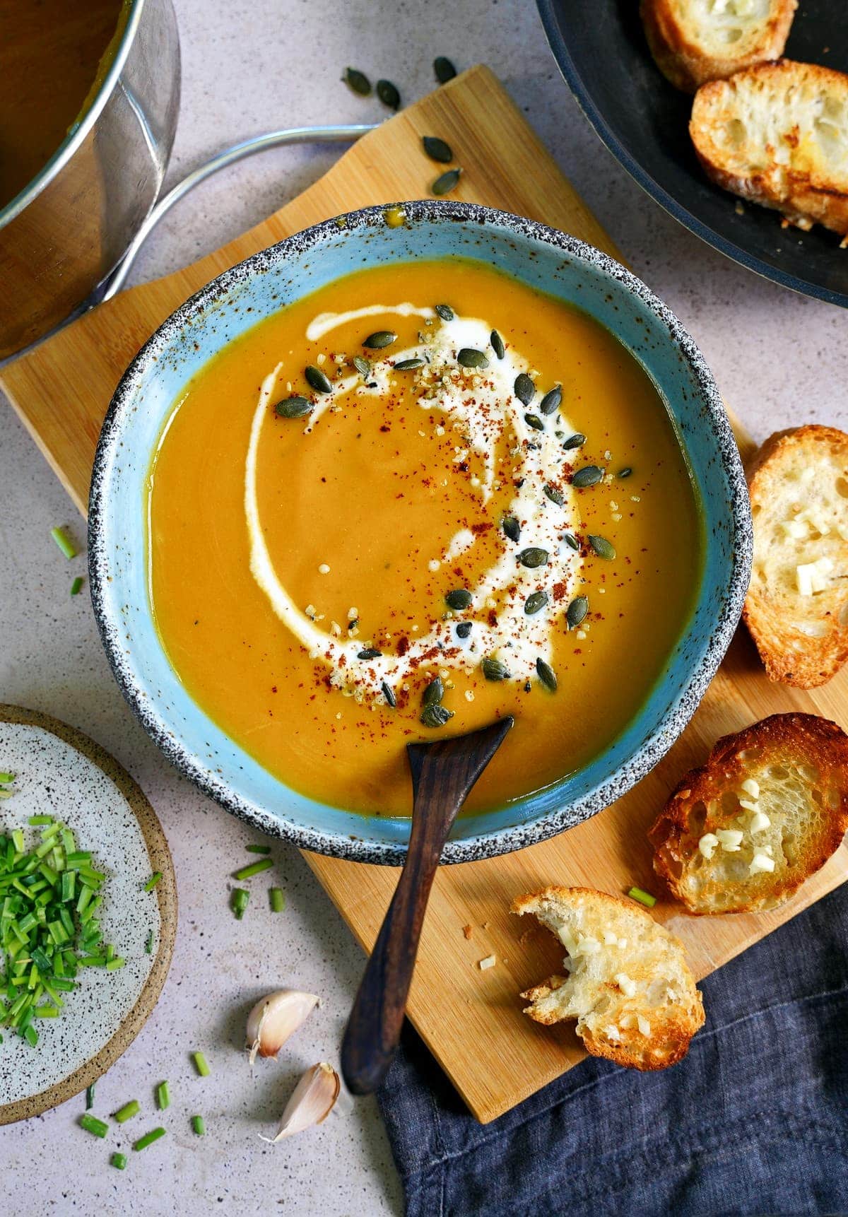 top shot of pumpkin soup with coconut drizzle, seeds and a spoon