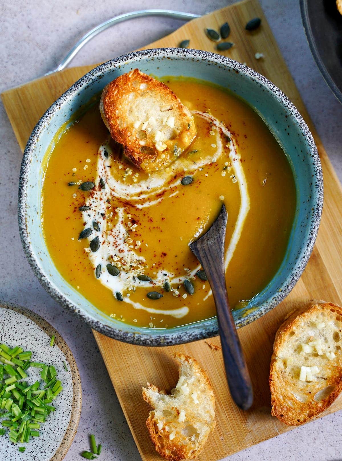 vegan pumpkin soup with bread and coconut drizzle