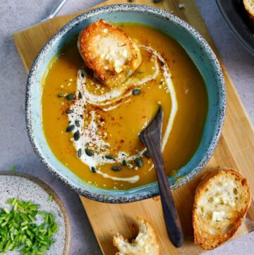 vegan pumpkin soup with crusty bread and coconut drizzle