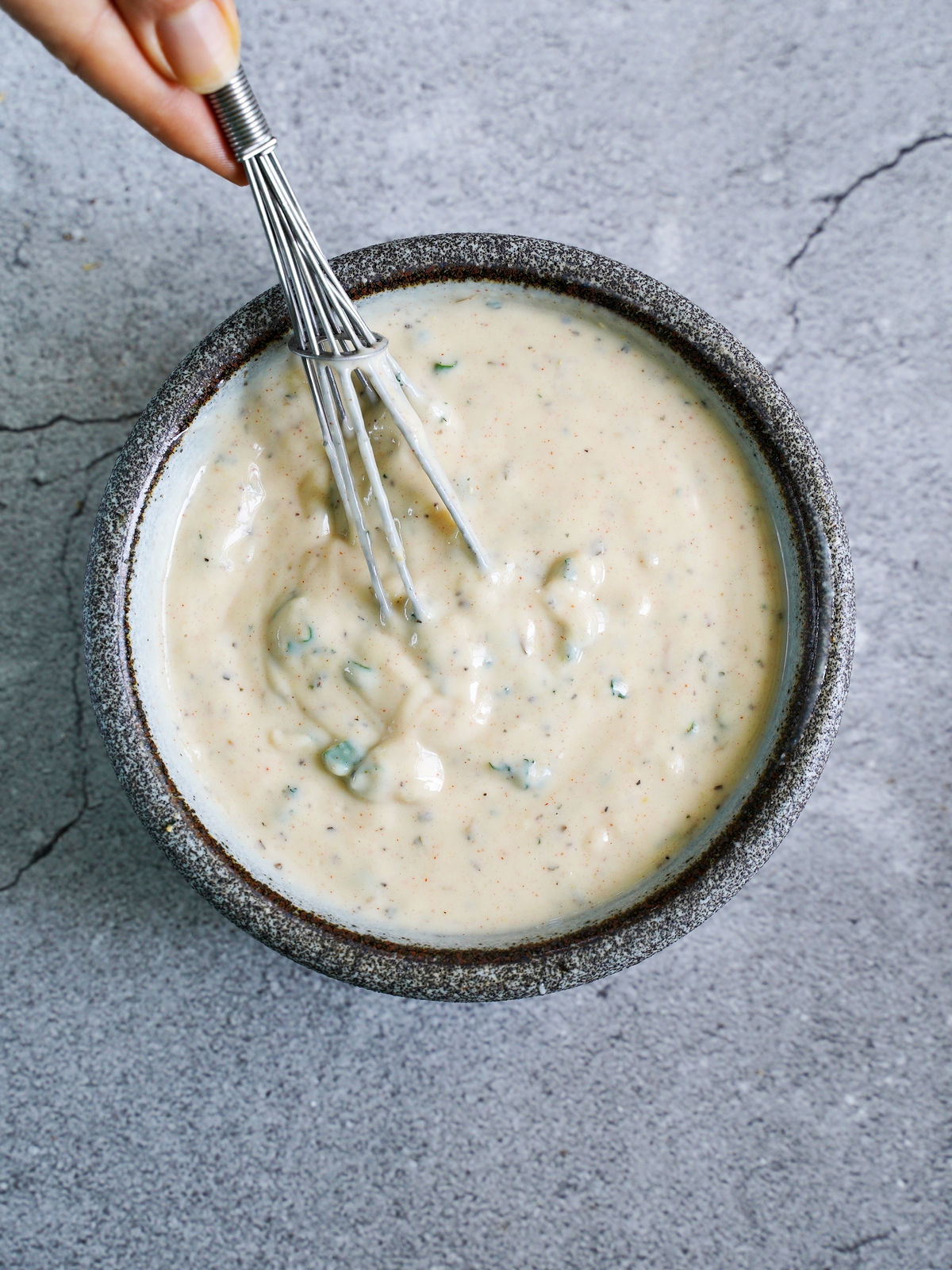 creamy salad sauce in bowl with whisk