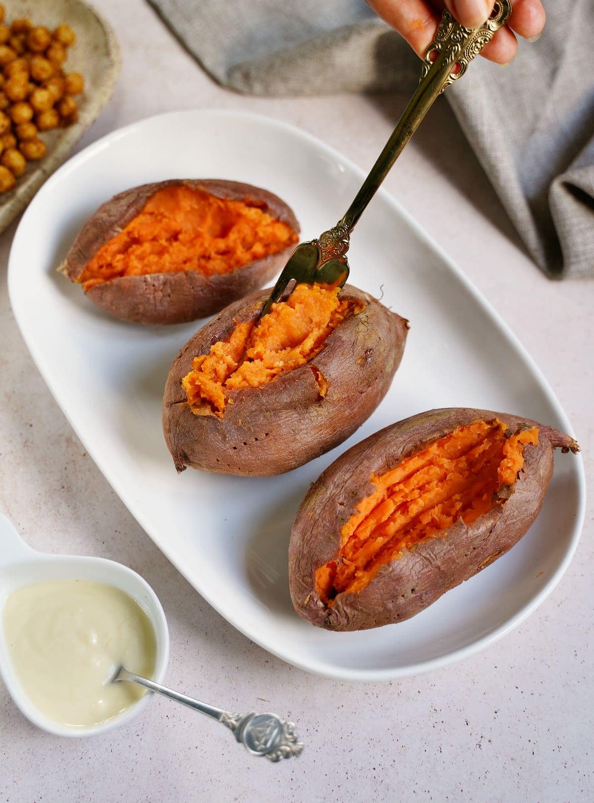Fluffing a baked sweet potato with a fork