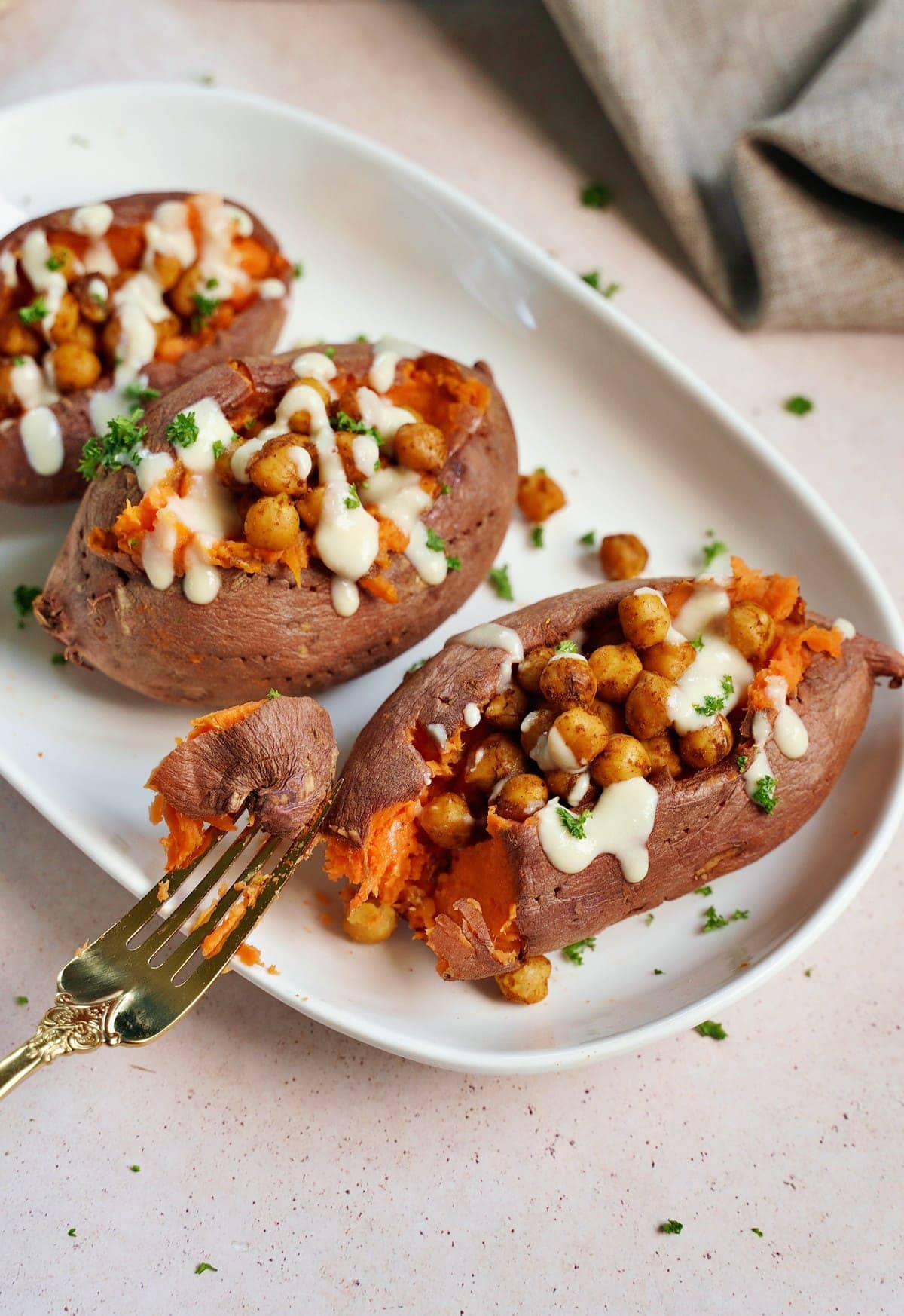 eating a baked sweet potato with roasted chickpeas and white sauce