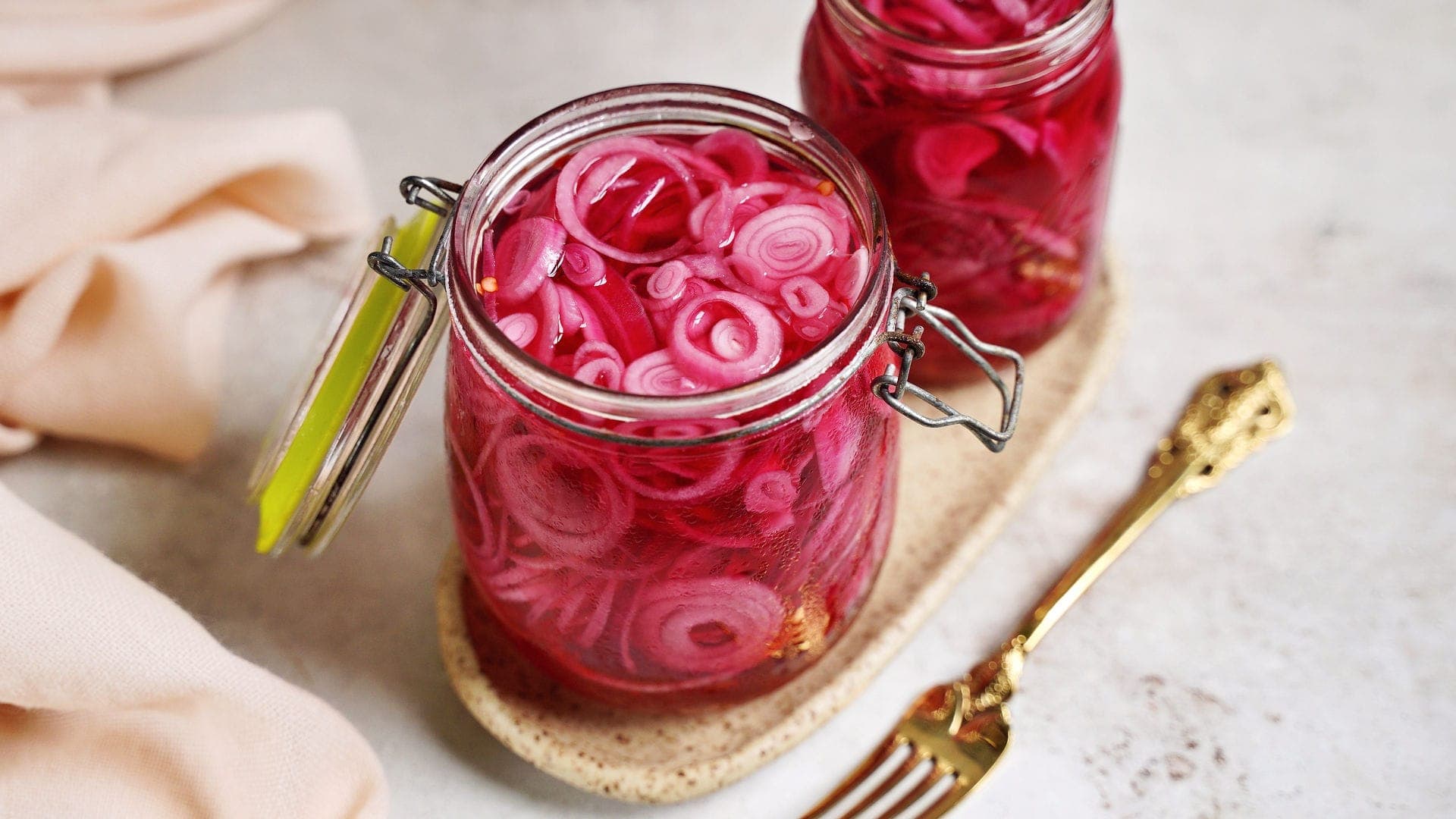 horizontal shot of red pickled onions in 2 jars