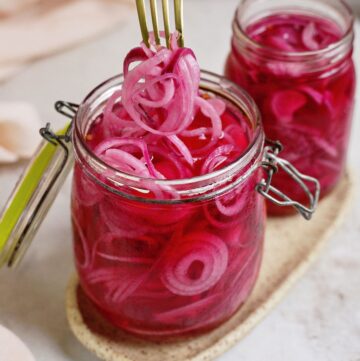 removing pickled red onions with fork from one large glass jars