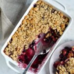 vegan blueberry apple crumble in white pan with large spoon