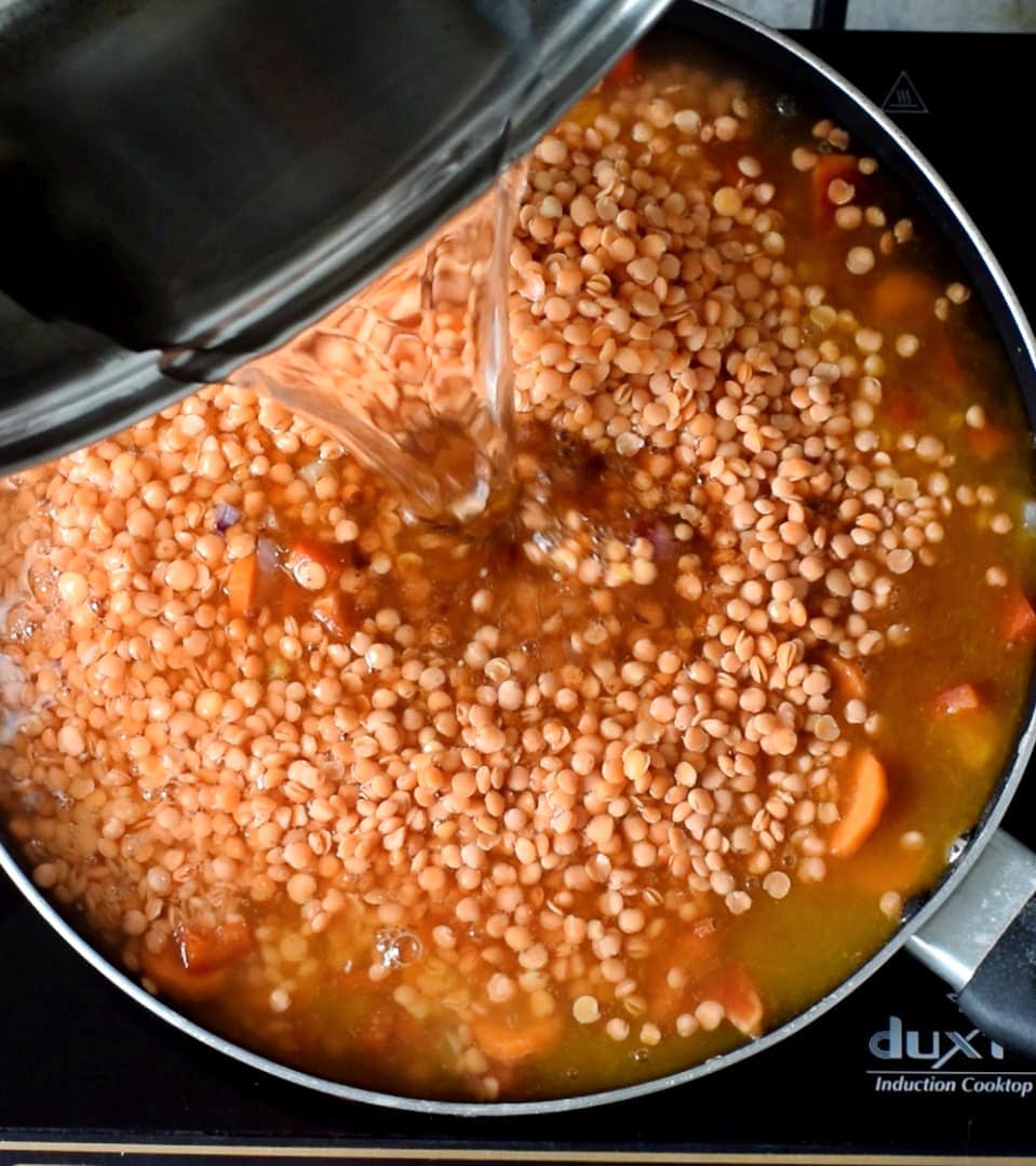 pouring water into pan with red lentils