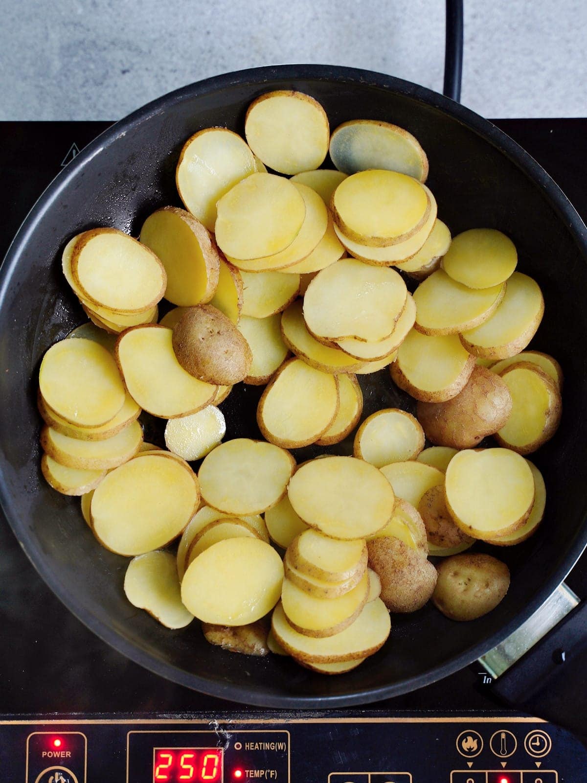 sliced cooked potato rounds in black frying pan