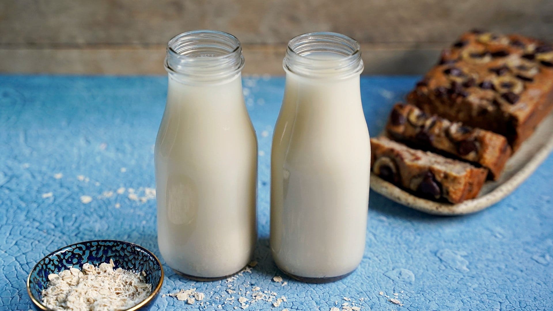 horizontal shot of 2 jars of homemade oat milk and banana bread
