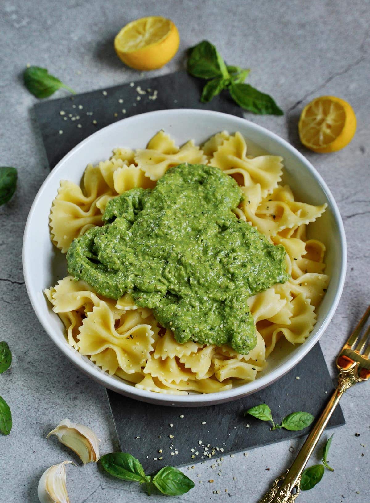 pasta in bowl with green basil avocado pesto in the middle