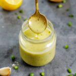 top shot of lemon vinaigrette in glass jar with spoon