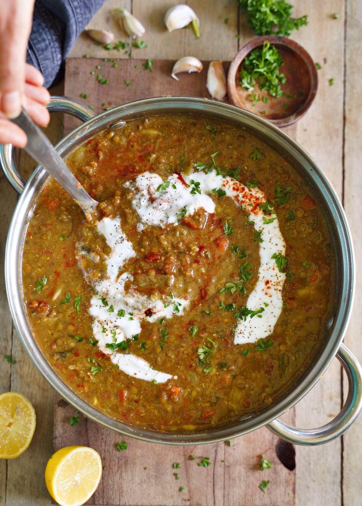 vegan lentil soup in large pot with coconut cream and ladle