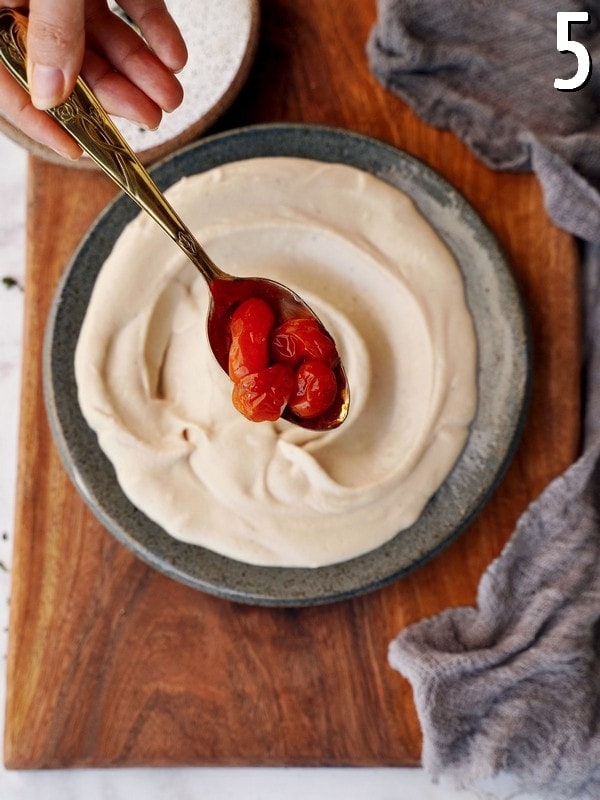 creamy dip in bowl with roasted tomatoes on spoon