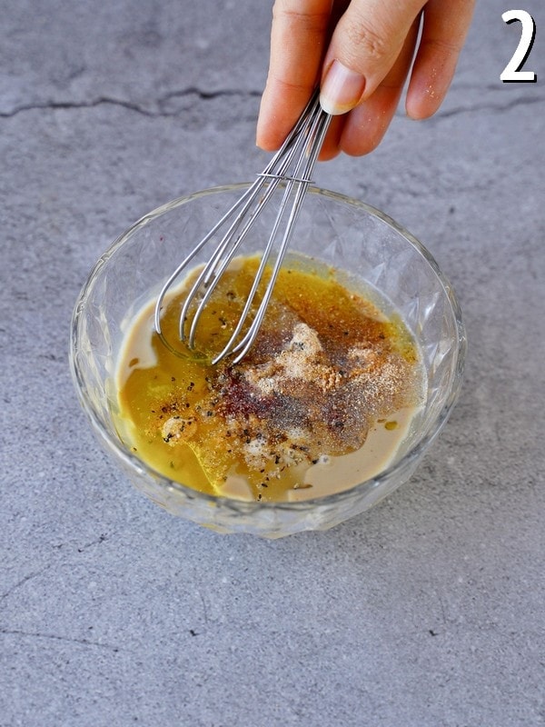 dressing ingredients in glass bowl with whisk