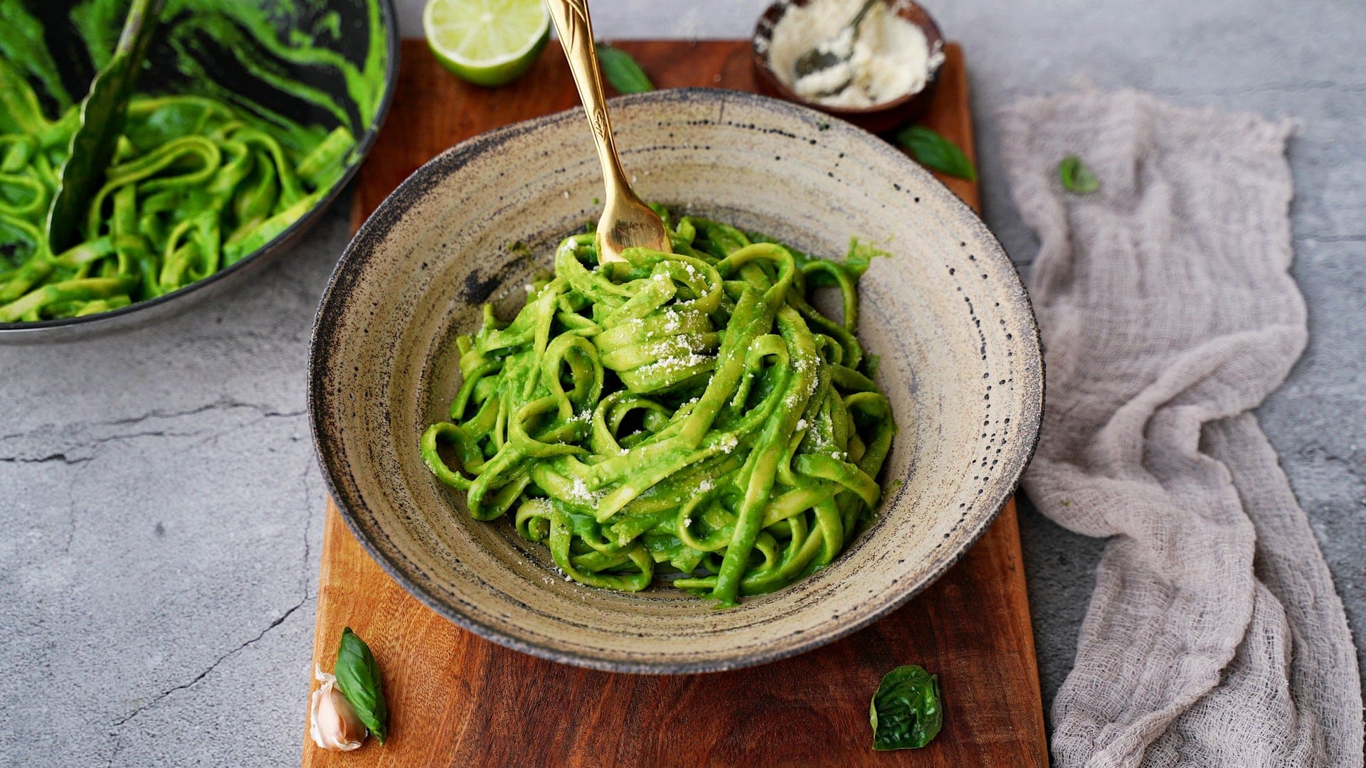 horizontal shot of creamy spinach pasta in bowl with fork