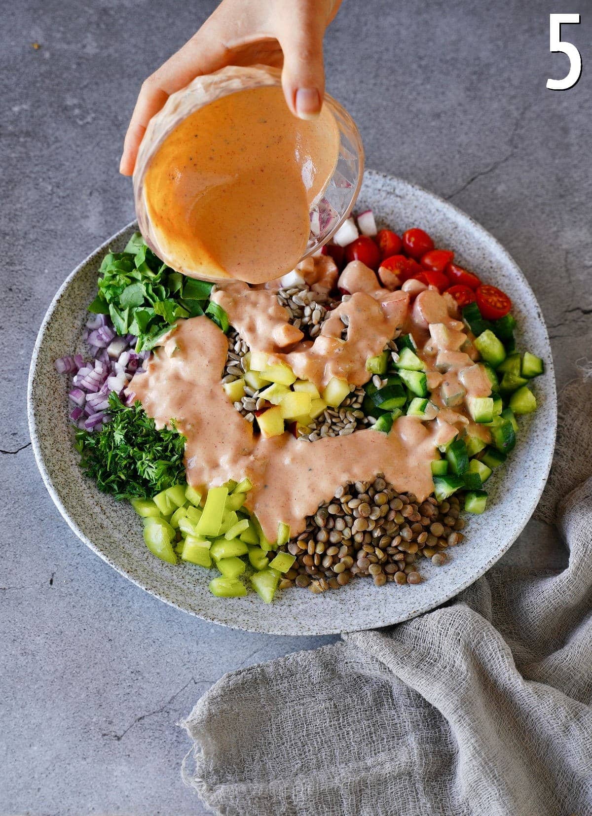 pouring dressing over salad with lentils