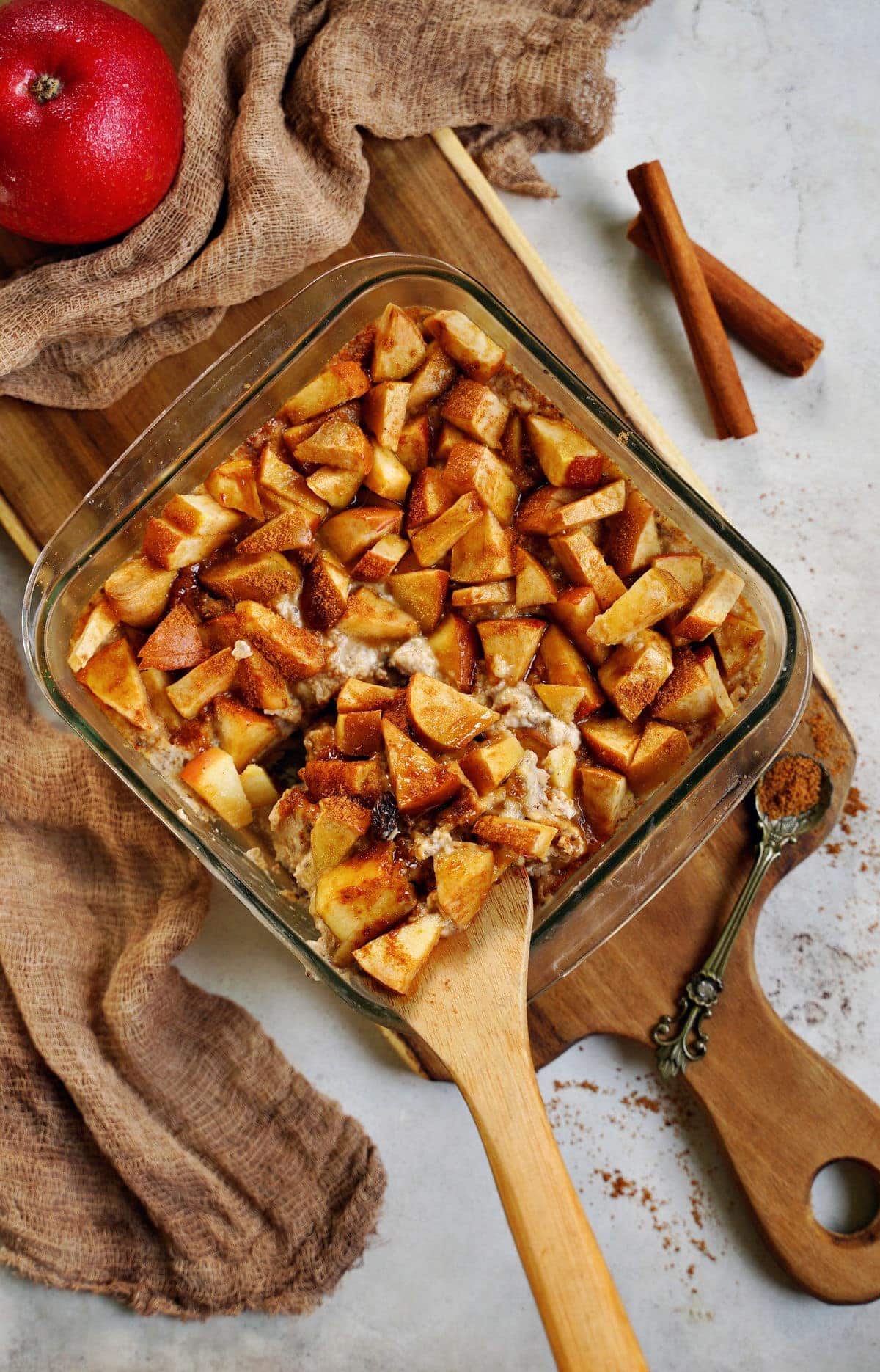 top shot of apple cinnamon baked oatmeal in pan with wooden spoon