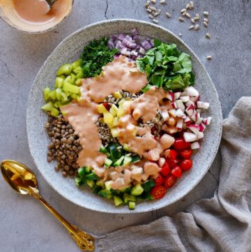 top shot of lentil salad on gray plate with tahini dressing