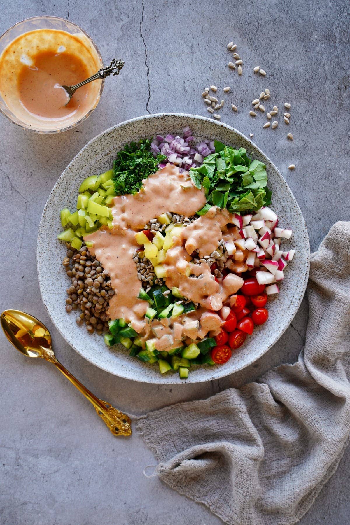top shot of vegan lentil salad on gray plate with tahini dressing