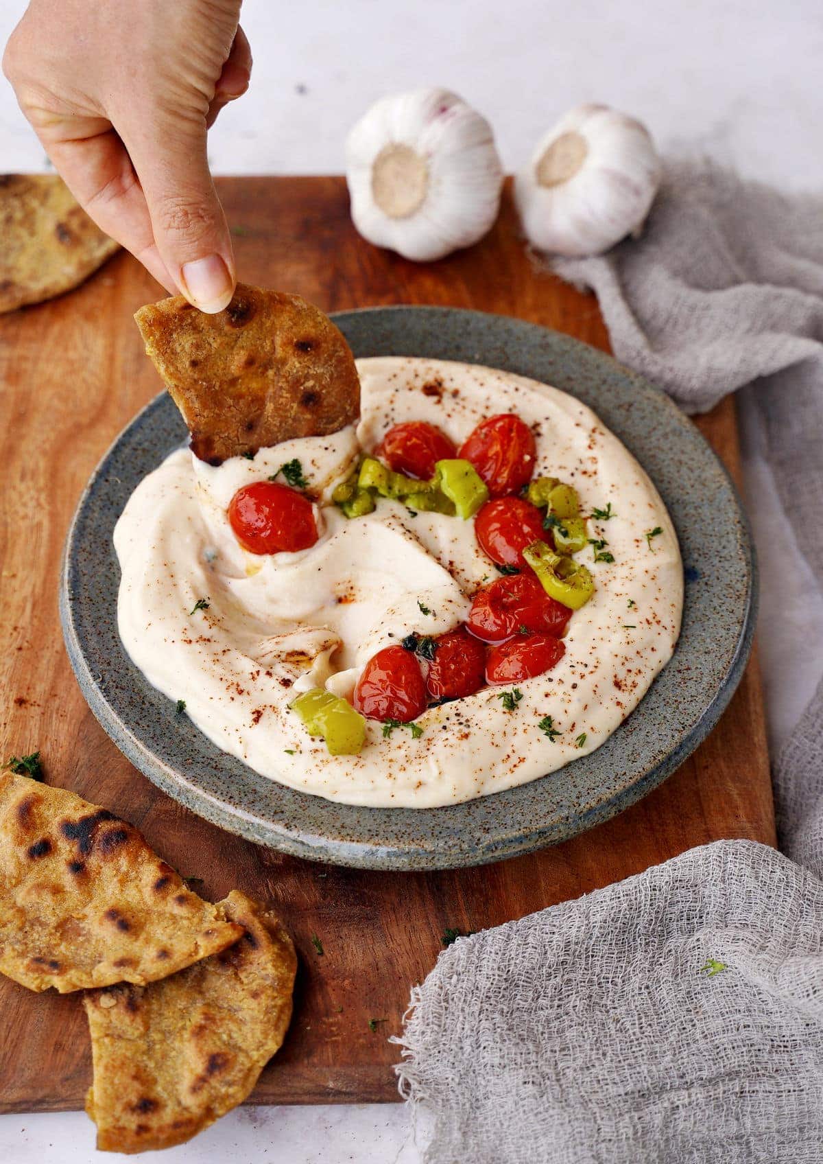 white bean dip in bowl with roasted veggies and flatbread