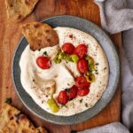 white bean dip with roasted garlic, tomatoes and pepper in bowl with flatbread