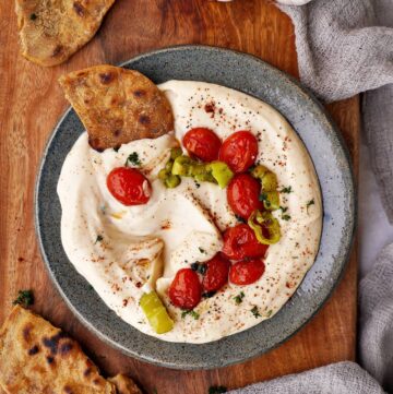 white bean dip with roasted garlic, tomatoes and pepper in bowl with flatbread