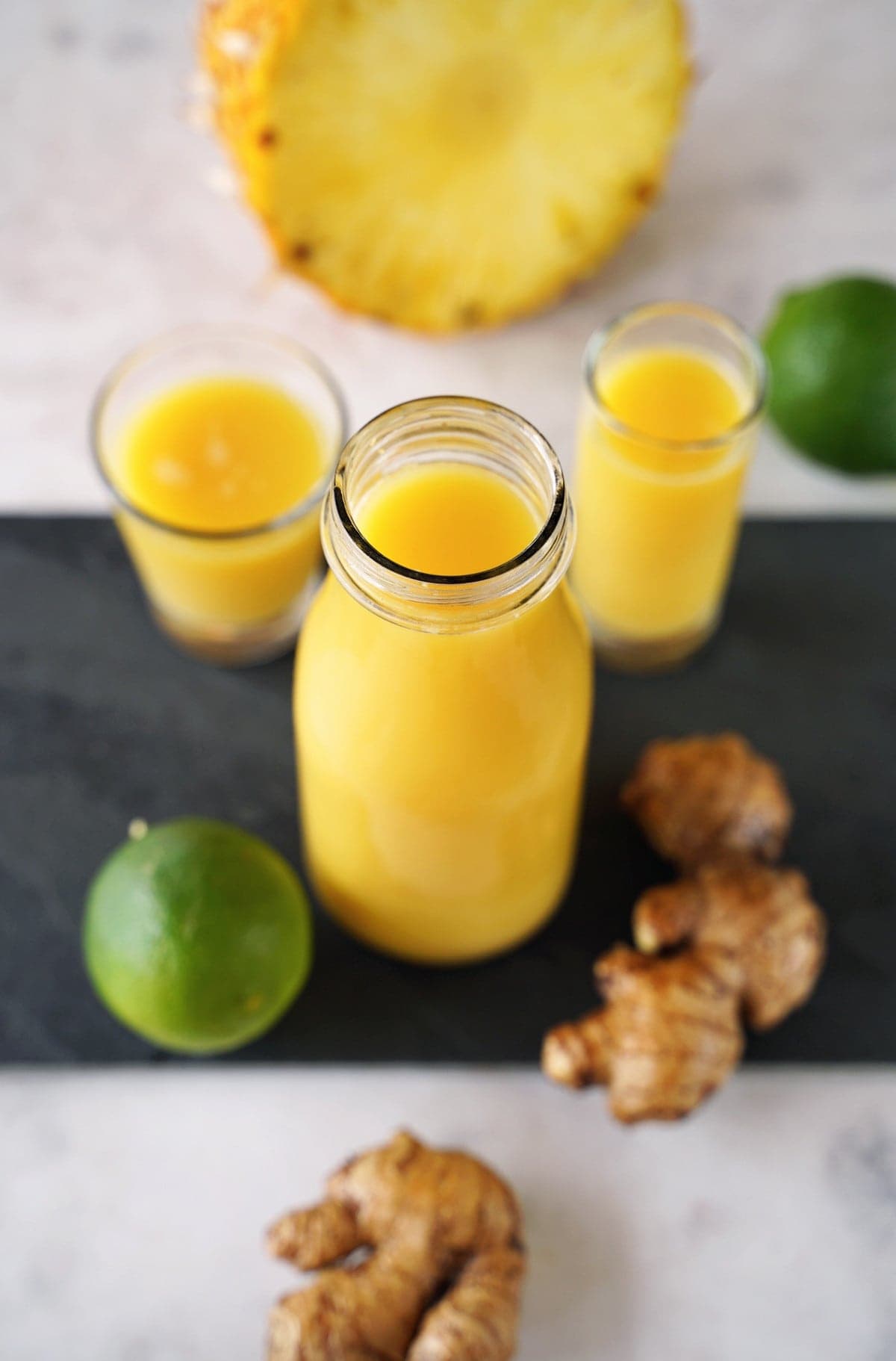 Glasflasche mit gelbem Ingwersaft und Dekoration aus Früchten 