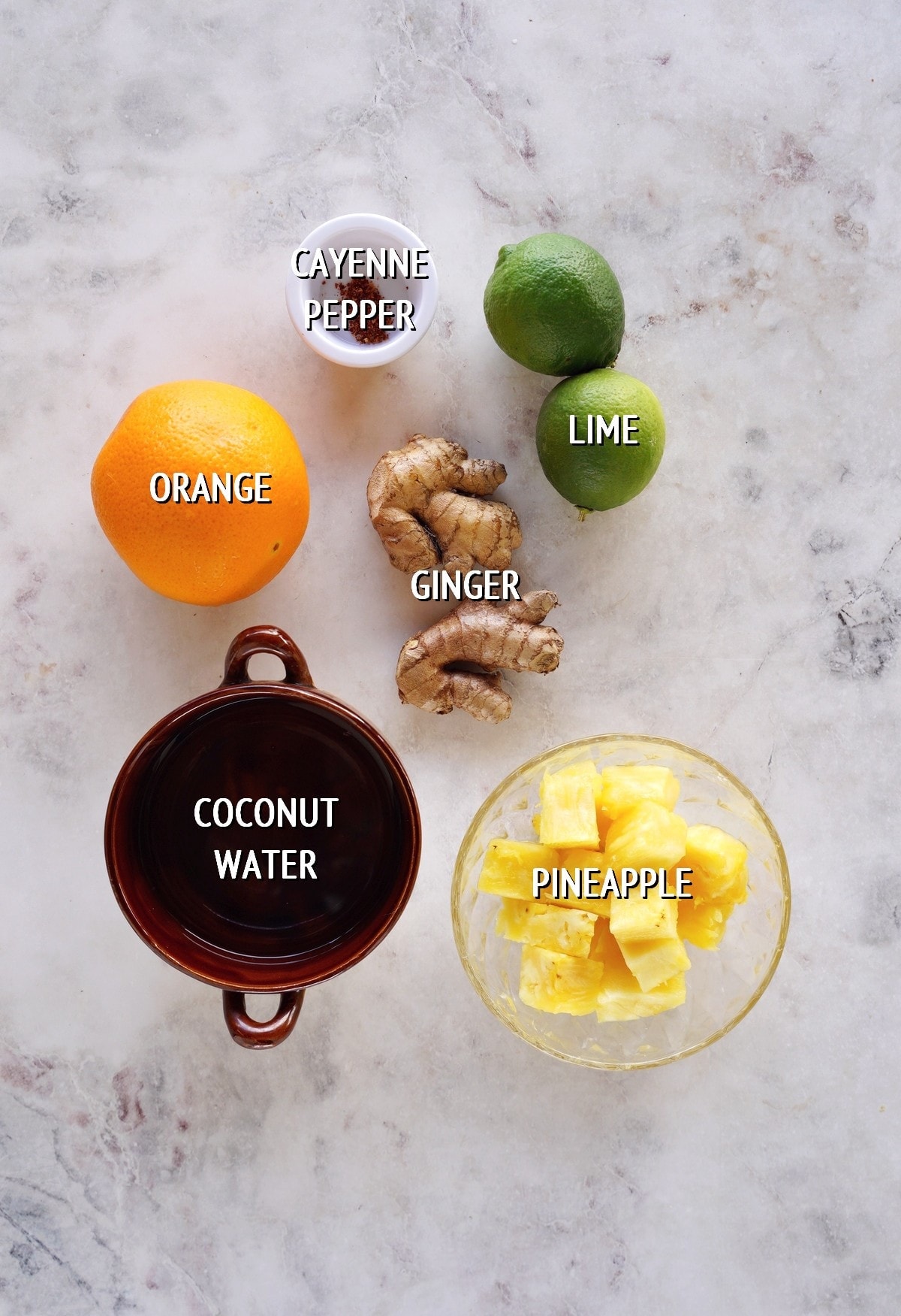 ingredients for ginger shots with labels on white marble backdrop