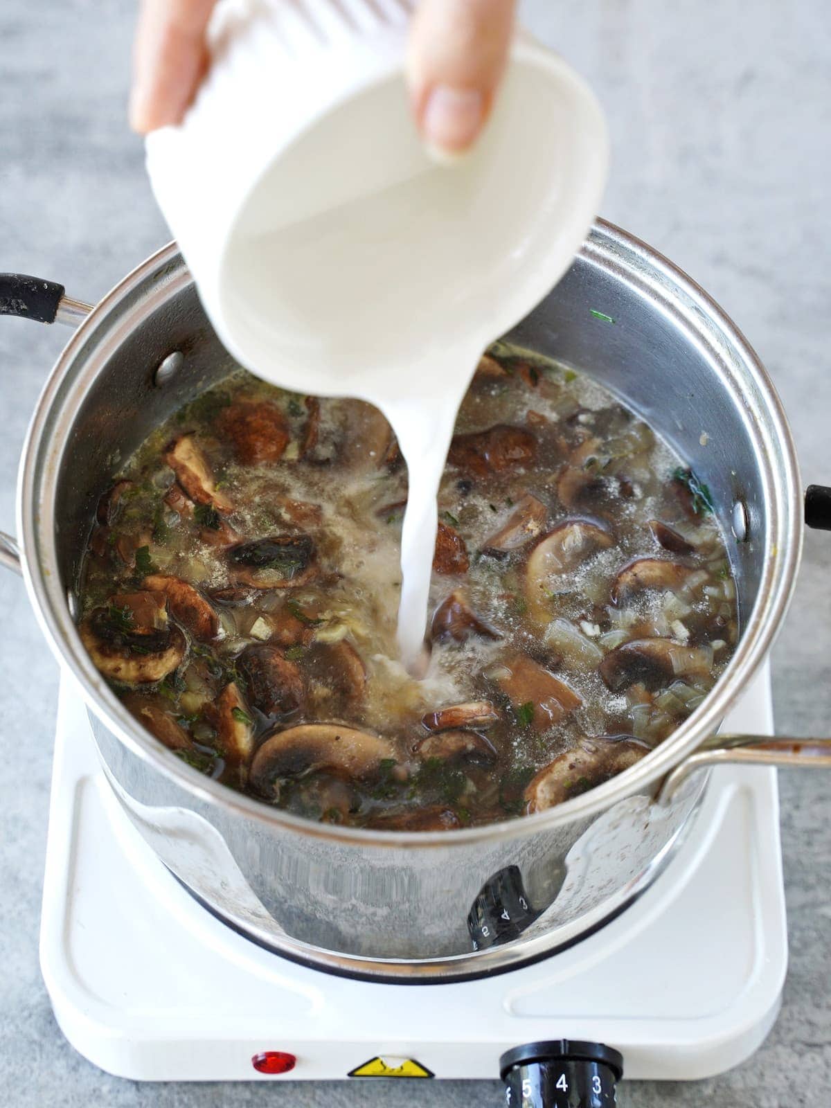 pouring dairy-free cream into mushroom soup