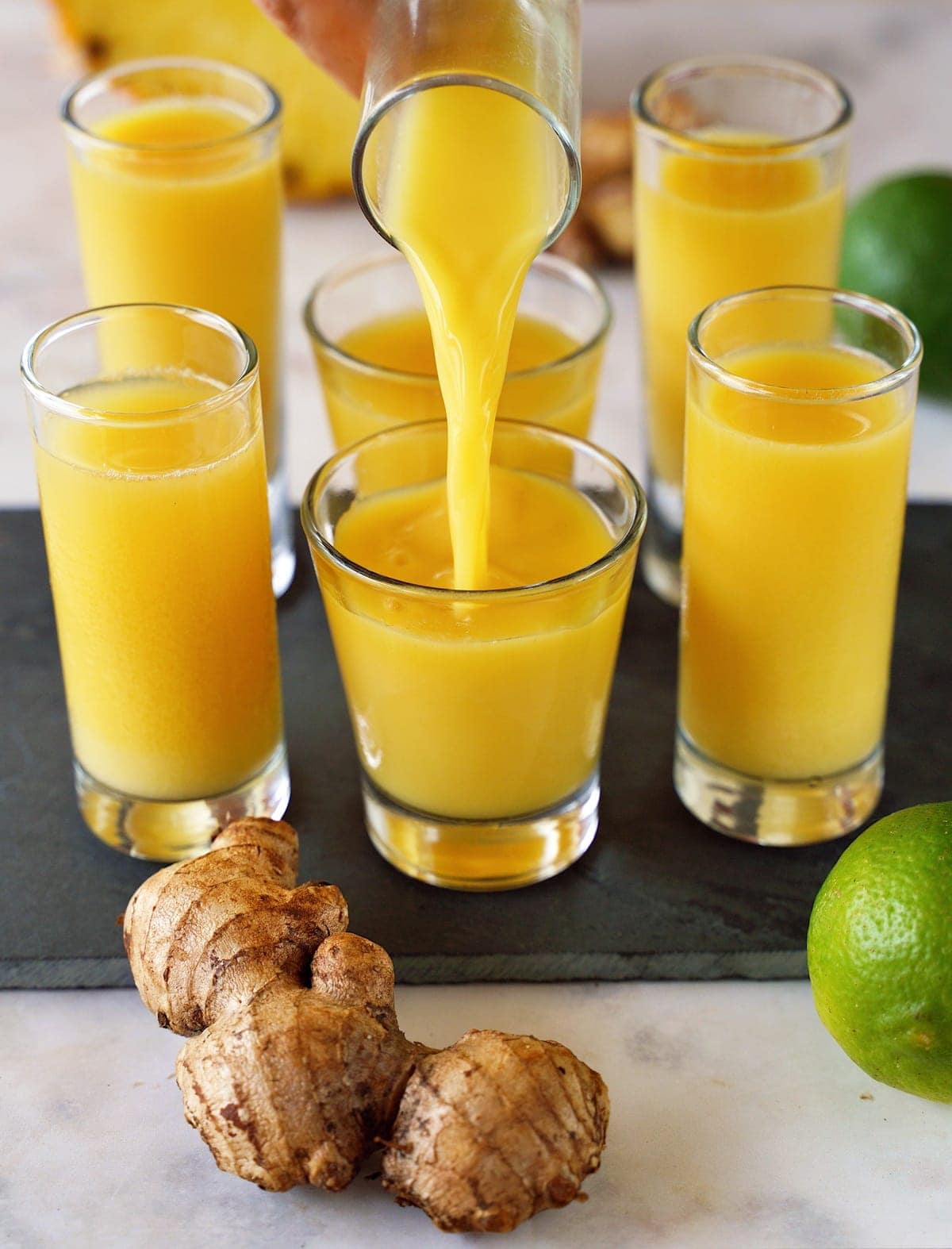 pouring ginger lime juice in a shot glass