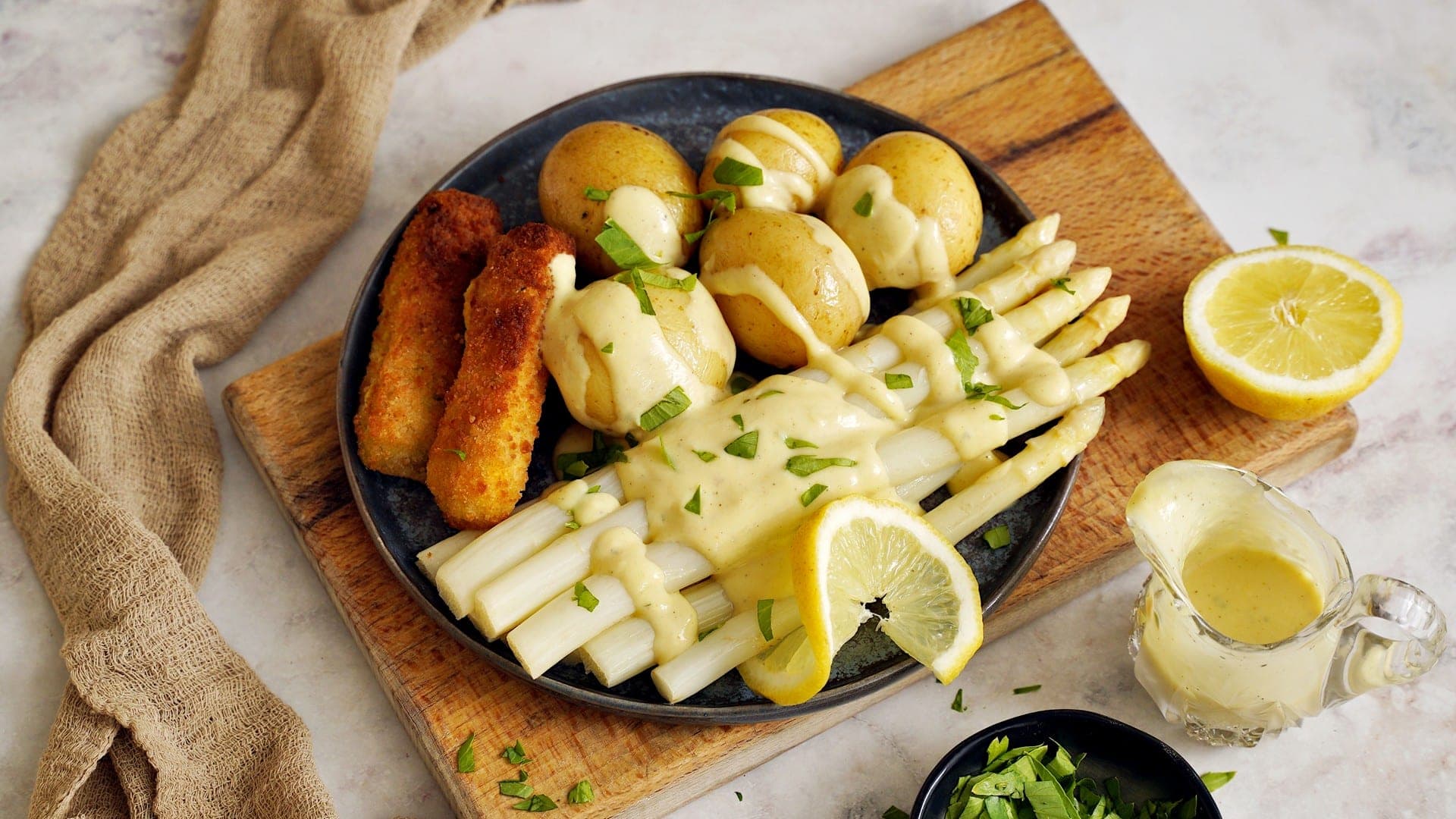 horizontal shot of plate with asparagus, potatoes, schnitzel and vegan hollandaise sauce